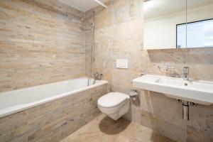 Un baño con inodoro, bañera y lavabo. en LAAX Homes - Casa Lanezzi 3, en Flims