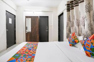 a bedroom with a large white bed with colorful pillows at FabHotel Vardhan House II in Dāpuri