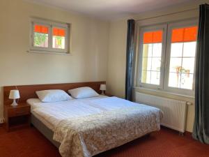 a bedroom with a bed with two pillows and two windows at Hotel Gryf in Kościerzyna