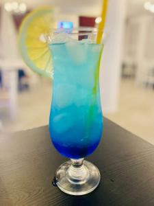 Perla Muntilor Ponoarele, Padurea de liliac في Ponoarele: مشروب أزرق في زجاج جالس على طاولة