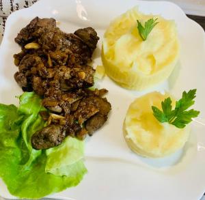 un plato de comida con carne y verduras. en Perla Muntilor Ponoarele, Padurea de liliac, en Ponoarele