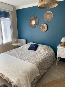 a bedroom with a bed with a blue wall at Les Valéricaines in Saint-Valéry-sur-Somme