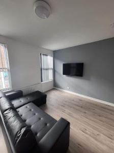 City Apartments Charles Street في هال: غرفة معيشة مع أريكة جلدية سوداء وتلفزيون بشاشة مسطحة