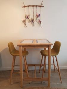 a wooden table with two chairs and some vases at Les Valéricaines in Saint-Valéry-sur-Somme