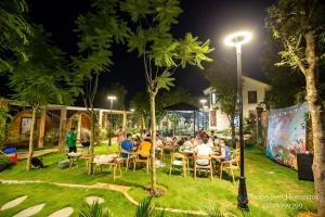 a group of people sitting at tables in a park at night at Phong Sơn Villa - Venuestay in Hanoi