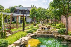 a garden with a pond in front of a house at Phong Sơn Villa - Venuestay in Hanoi