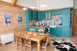 a kitchen with blue cabinets and a wooden table and chairs at Villa Raphael near the Bansko Ski Resort in Razlog