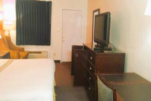 Dormitorio con cama y tocador con TV en OYO Hotel McIntyre GA, US 441, en McIntyre