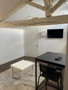 a room with a table and a chair and a tv at Les Studios de Clément in Poitiers