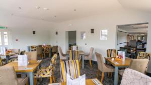 uma sala de jantar com mesas e cadeiras de madeira em The Appleby Inn Hotel em Appleby Magna