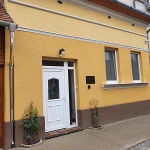 a yellow building with a white door and windows at Jégmadár Apartman in Debrecen