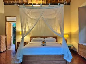 - une chambre dotée d'un lit à baldaquin avec un ours en peluche dans l'établissement Desa Kerasan 5 -Luxury 2BRV 15 mins to Ubud, à Ubud