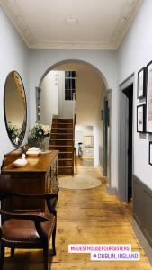 - un couloir avec une table, un miroir et des escaliers dans l'établissement Old Dublin ‘Four sisters’, à Dublin