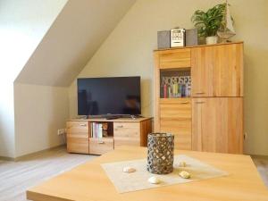 a living room with a tv and a table at Hus-Pellworm-2-Ferienwohnung-Meereswelle in Pellworm