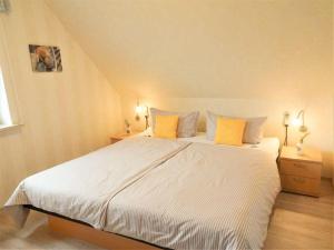 1 dormitorio con 1 cama blanca grande con almohadas amarillas en Hus-Pellworm-2-Ferienwohnung-Meereswelle en Pellworm