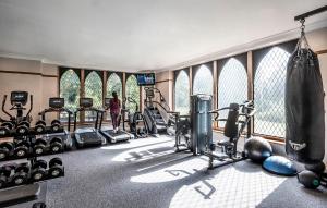 a gym with treadmills and weights and a woman in the background at New Hall Hotel & Spa, Birmingham in Birmingham