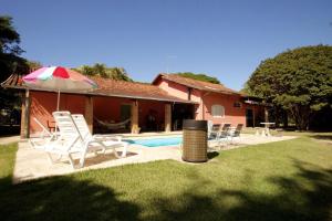 Una piscina con sillas y una sombrilla al lado de una casa. en Piscina e muito lazer em linda Chacara, Franca SP, en Franca