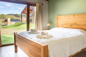 a bedroom with a large bed with a large window at Cabañas La Catalana in Tandil +30 photos