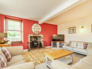 a living room with red walls and a fireplace at Anglers Cottage in Skipton