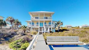 a large yellow house on the beach with a bench at Barefoot Bungalow in St. George Island