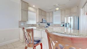 a kitchen with white cabinets and a counter with two chairs at Barefoot Bungalow in St. George Island