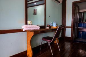 a wooden table with a chair and a mirror at Nongsak Riverside Guesthouse & Nongsak Guesthouse in Ban Khon