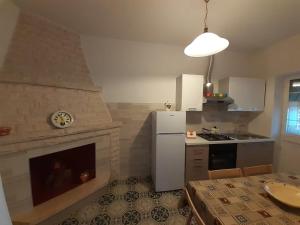 a kitchen with a fireplace and a white refrigerator at La mia Dimora in Cocolicchio