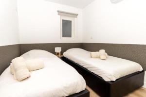 two beds in a room with white sheets and towels at Oporto Modern Apartments - Campanha Train Station in Porto