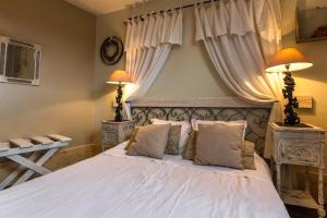 a bedroom with a large white bed with two lamps at La Palette Fleurie in Laignes