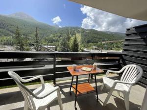 a table and two chairs on a balcony with mountains at Appartement Saint-Chaffrey , 1 pièce, 4 personnes - FR-1-330E-95 in Saint-Chaffrey