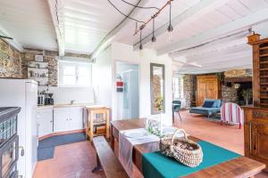 een keuken met witte kasten en een tafel in een kamer bij La Villauvert - Cottage in Saint-Martin-sur-Oust