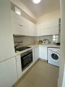 a white kitchen with white cabinets and a dishwasher at Suite Apartment Vlorë in Vlorë