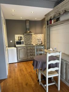 a kitchen with a table and chairs and a refrigerator at Hôtel La Vinaigrerie LOGIS in Joinville
