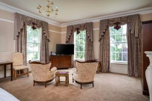 een kamer met 2 stoelen, een televisie en ramen bij St Nicholas House in Spalding