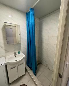 La salle de bains est pourvue d'un rideau de douche bleu et d'un lavabo. dans l'établissement Затишна Smart-Квартира, à Kiev