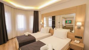 Habitación de hotel con 2 camas y espejo en Alesta Seaside Residence, en Fethiye