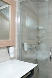uma casa de banho com um chuveiro, um lavatório e um espelho. em Alesta Seaside Residence em Fethiye