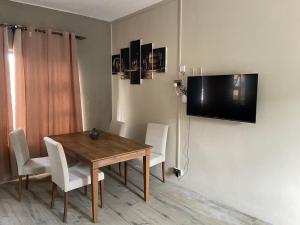 a dining room with a table and a television on the wall at City Apartments in Port Louis