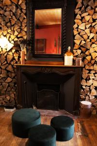 a fireplace with two stools in front of a mirror at Eau Berges in Vicdessos