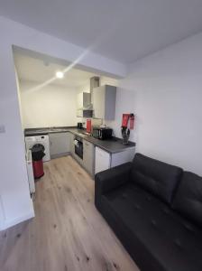 a living room with a black couch in a kitchen at City Apartments Charles Street in Hull