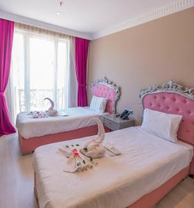 twee bedden in een kamer met roze gordijnen bij Sarot Thermal Palace Tatil Köyü - Halal Hotel in Karacasumandıra