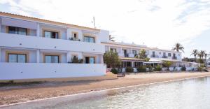 a large white building next to a body of water at Hostal la Savina in La Savina