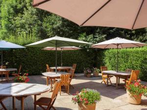 a patio with tables and chairs with umbrellas at ibis Velizy Jouy-En-Josas in Jouy-en-Josas