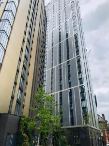 a tall glass building with trees in front of it at Lovely One Bedroom Apartment on Broad Street! in Birmingham