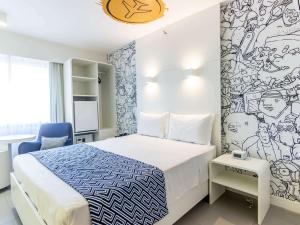 um quarto com uma cama e uma parede com um mural em ibis Styles Rondonopolis em Rondonópolis