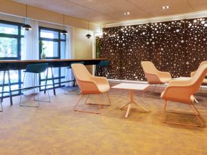 une salle d'attente avec des chaises et une table ainsi qu'un mur avec des points dans l'établissement Mercure Perpignan Centre, à Perpignan