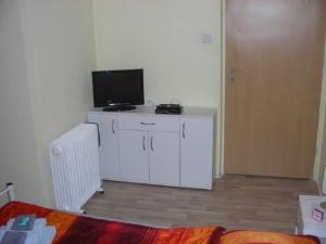 a living room with a television and a white cabinet at Kleine FEWO zentral gelegen in Künzell