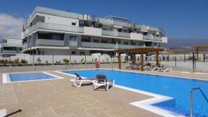 een zwembad met stoelen en een gebouw bij Calm Home La Tejita in Granadilla de Abona