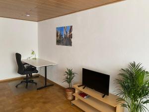 Habitación con escritorio, TV y silla. en Ferienwohnung Stiegel en Ingelheim am Rhein