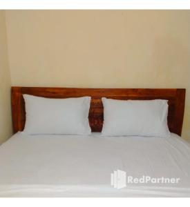a bed with two white pillows and a wooden headboard at Navisha Guest House Syariah near Exit Tol Batang RedPartner in Pekalongan